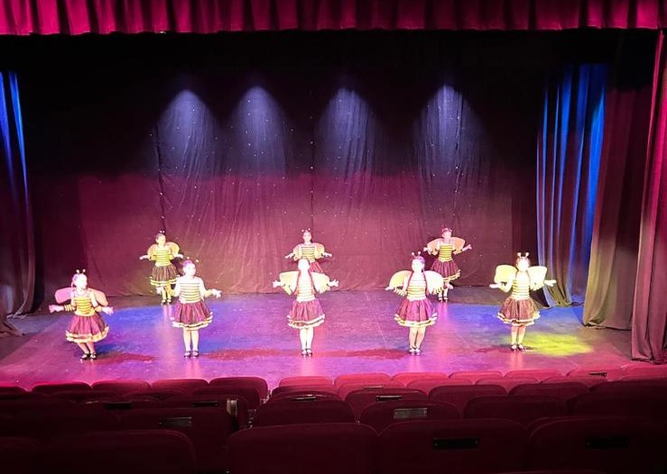 Large ensemble dance number with colourful costumes on stage